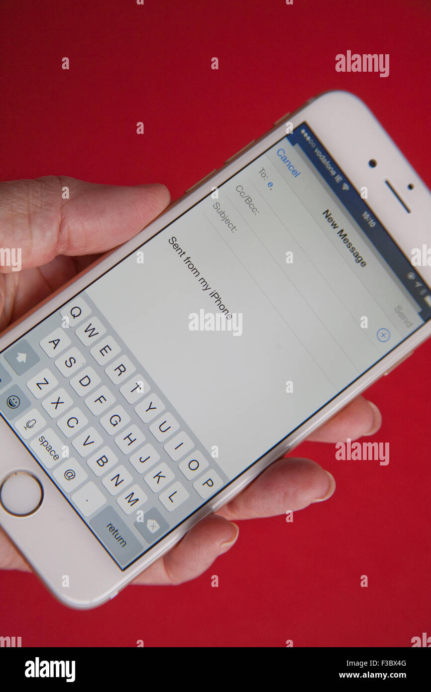 Senden einer e-Mail auf eine goldene und weiße Apple iPhone 6 auf rotem Grund Stockfoto