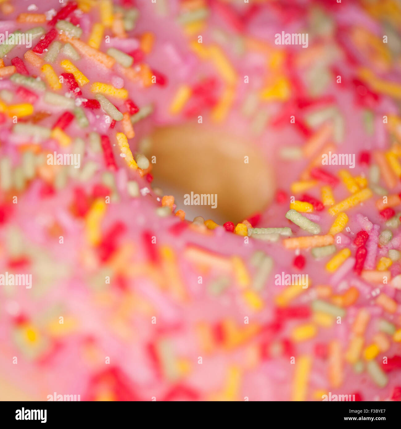 Nahaufnahme von einem rosa Ring Donut mit farbigen Hunderten und Tausenden Stockfoto