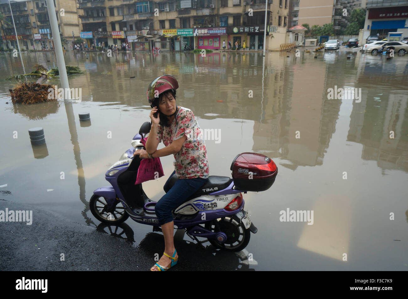 (151005)--ZHANJIANG, 5. Oktober 2015 (Xinhua)--A Motorradfahrer Makes Taifun Mujigae in Zhanjiang Stadt, Süd-China Guangdong Provinz, 4. Oktober 2015 ein Anruf auf einer überfluteten Straße zurückzuführen. Ein Fischer starb und weitere 16 fehlen als Taifun Mujigae, 22. Taifun in diesem Jahr bildete Landfall in der südchinesischen Provinz Guangdong am Sonntag. Ab 19:30 Sonntag meldeten 35 Fälle von Boot Verseilung und Anker ziehen aus den Gewässern von Zhanjiang Stadt mit 117 Fischer gerettet und 16 fehlen noch, nach Zhanjiang maritime Rescue Center. Drei Menschen starben ein Stockfoto