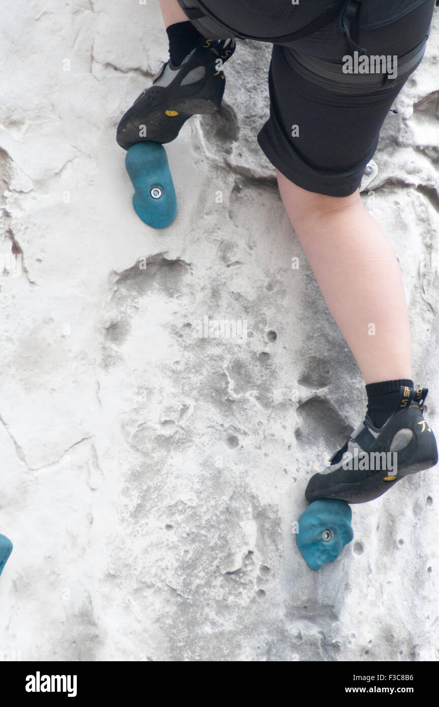 Junges Teen Mädchen klettert auf eine künstliche Kletterwand Nahaufnahme von den Füßen und spezielle Kletterschuhe Stockfoto
