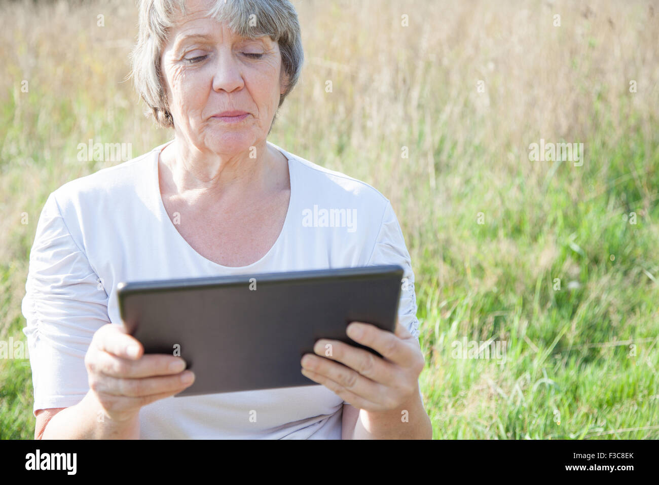Alter Frau mit Tablet-Gerät Stockfoto