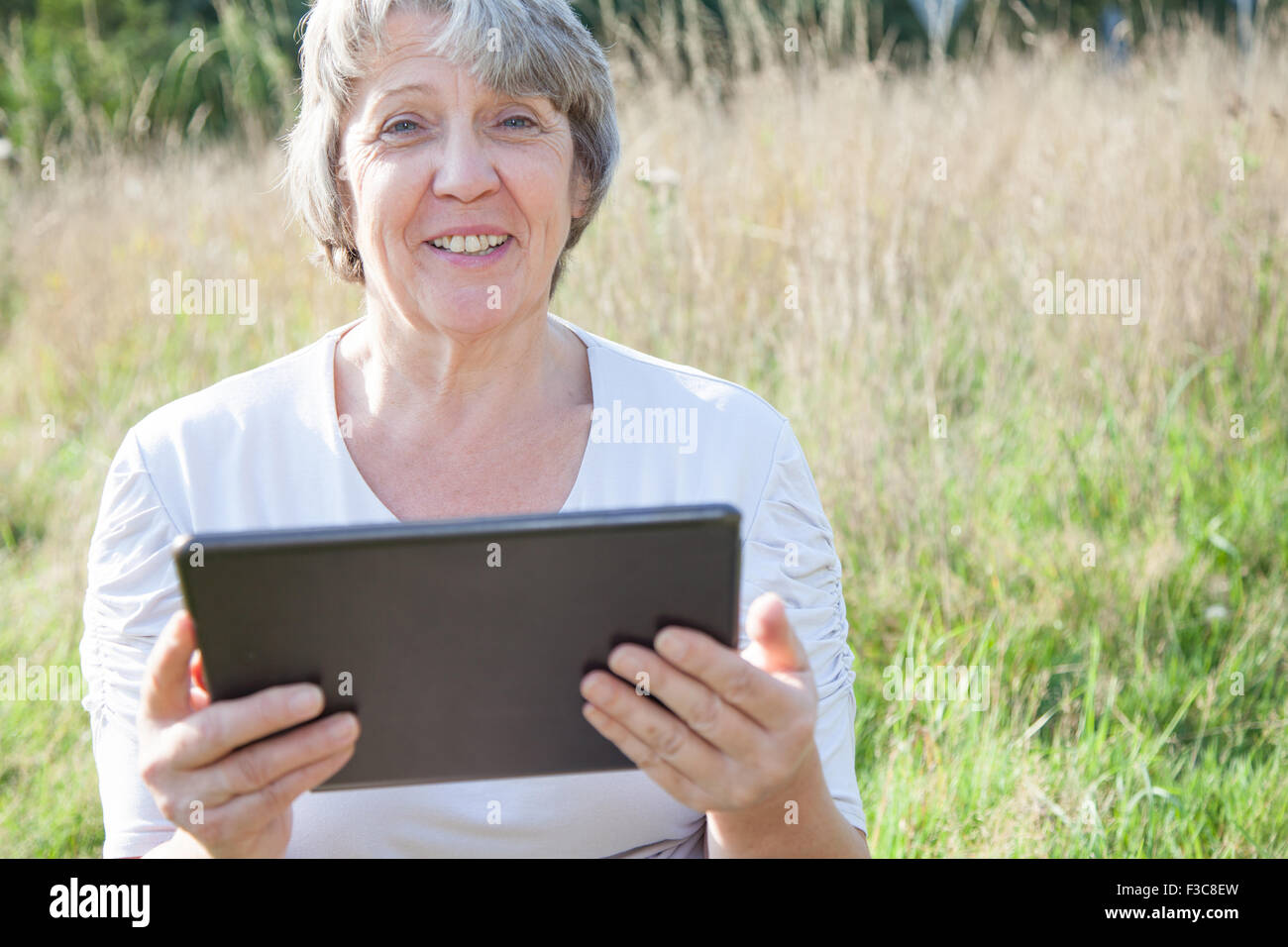 Alter Frau mit Tablet-Gerät Stockfoto