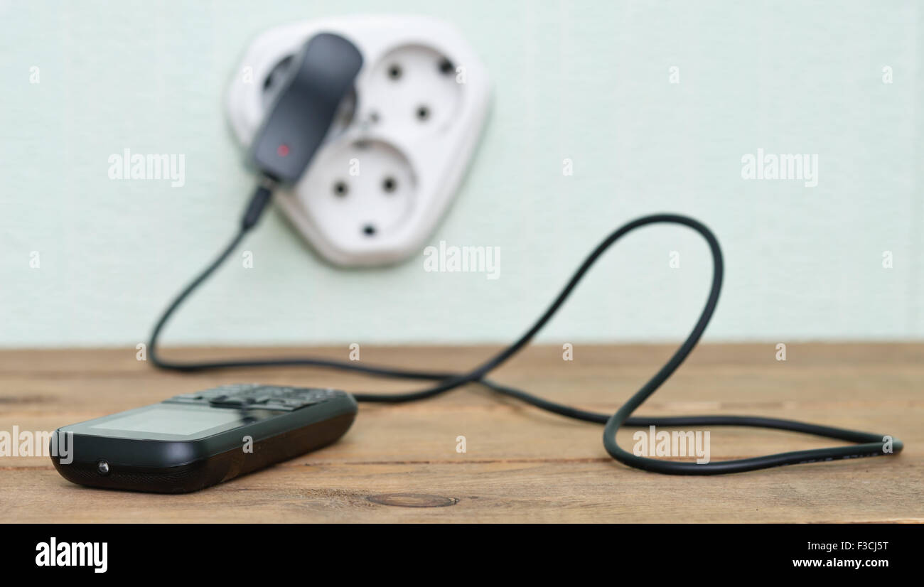 Handy aufladen mit Kabel auf dem Holztisch Stockfoto