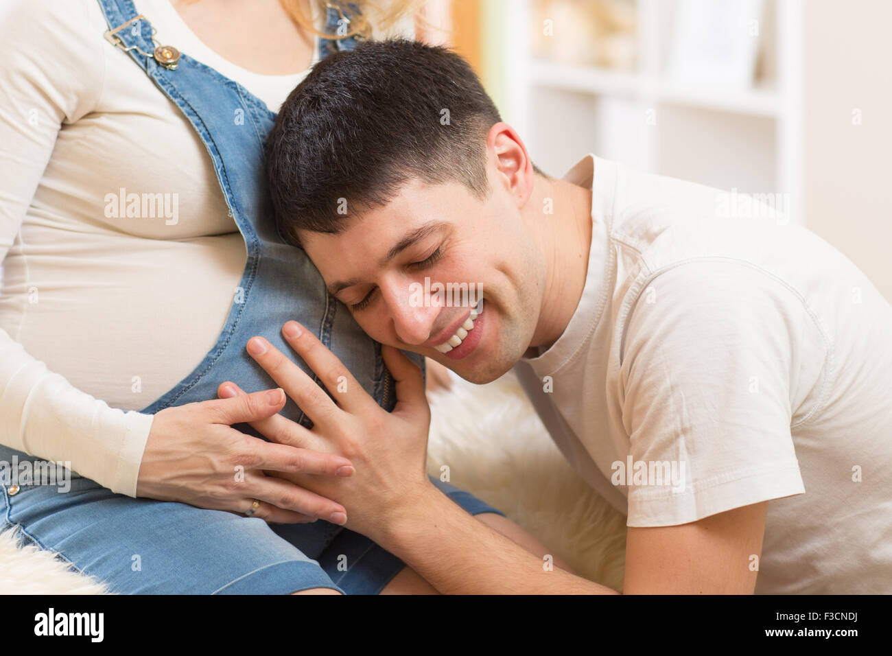 Glücklicher Mann Bauch seiner schwangeren Frau anhören Stockfoto