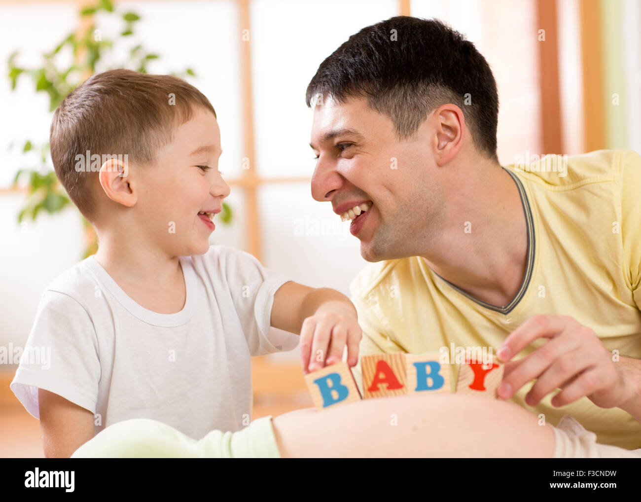 Kind junge und sein Vater spielen mit Würfeln am Bauch der schwangeren Mutter Stockfoto