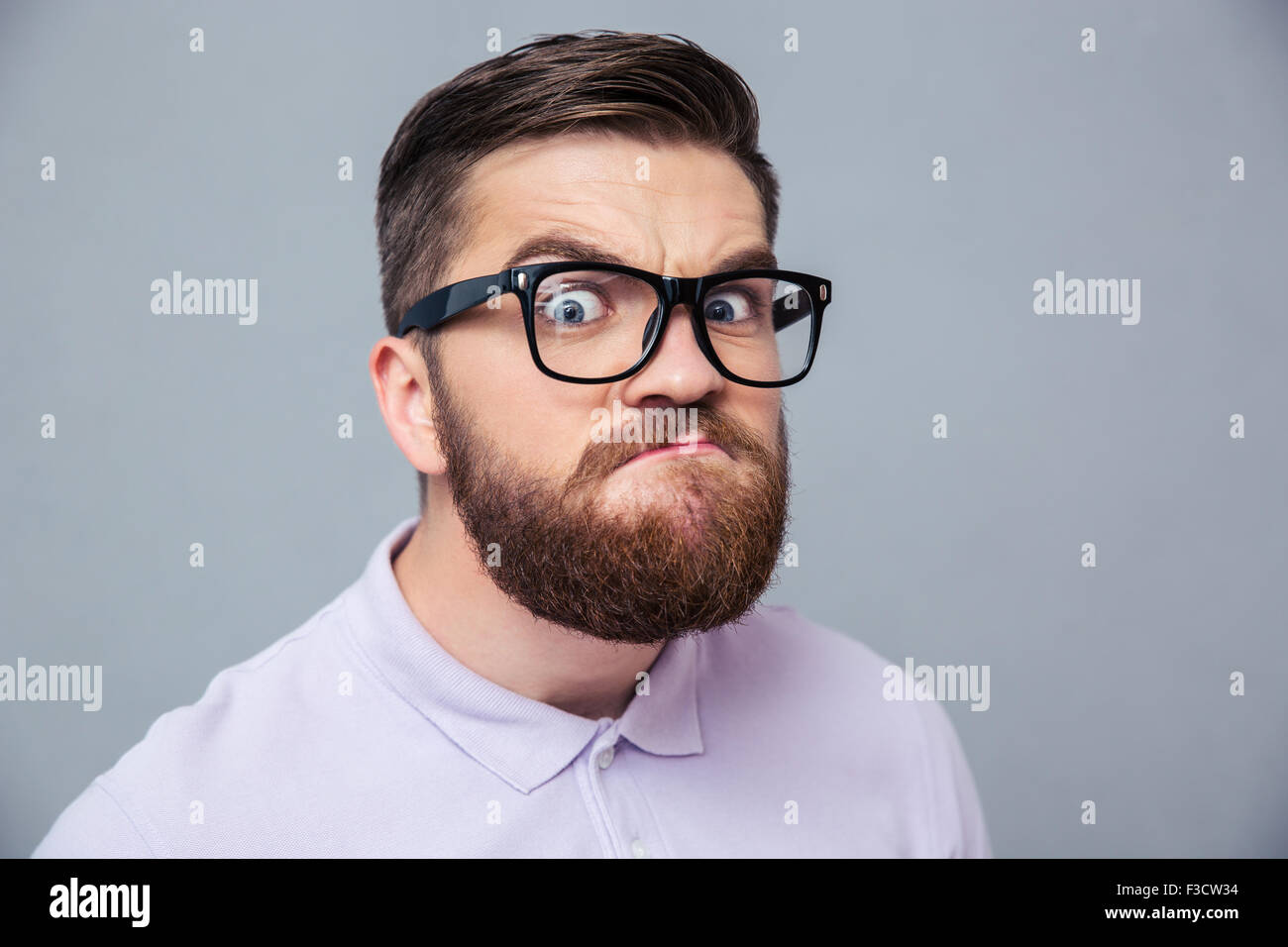 Porträt eines lustigen Hipster Blick in die Kamera über den grauen Hintergrund Stockfoto