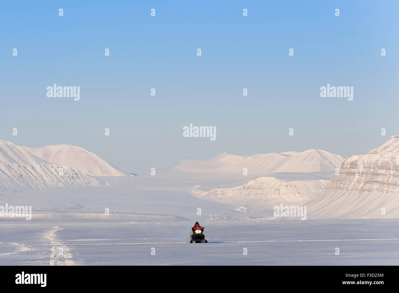 Mann mit Motorschlitten auf dem Weg in einer verschneiten Landschaft mit Tunabreen Gletscher hinter Tempelfjorden, Spitzbergen, Svalbard, Nr. Stockfoto