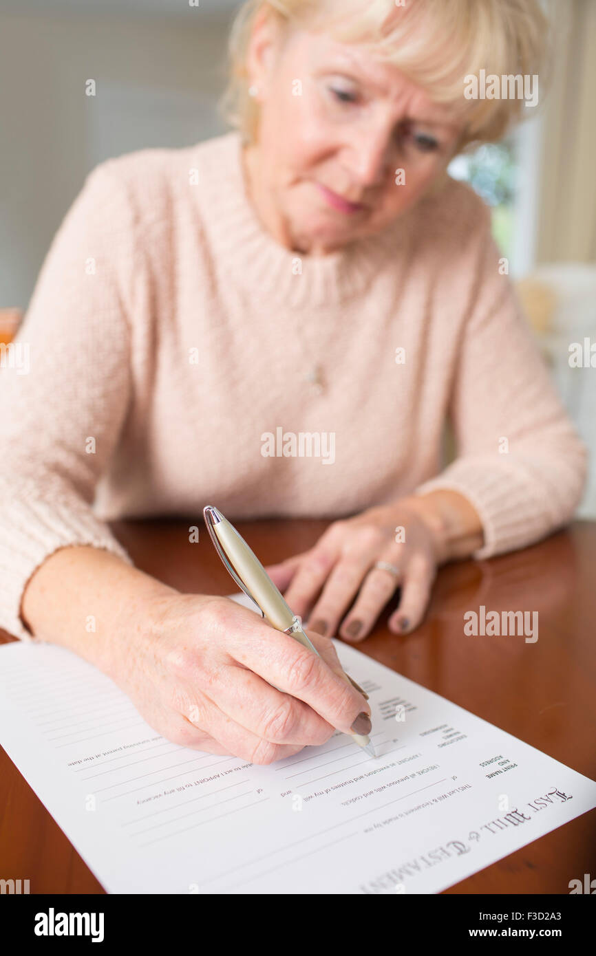 Ältere Frau Unterzeichnung letzten Willen und Testament zu Hause Stockfoto