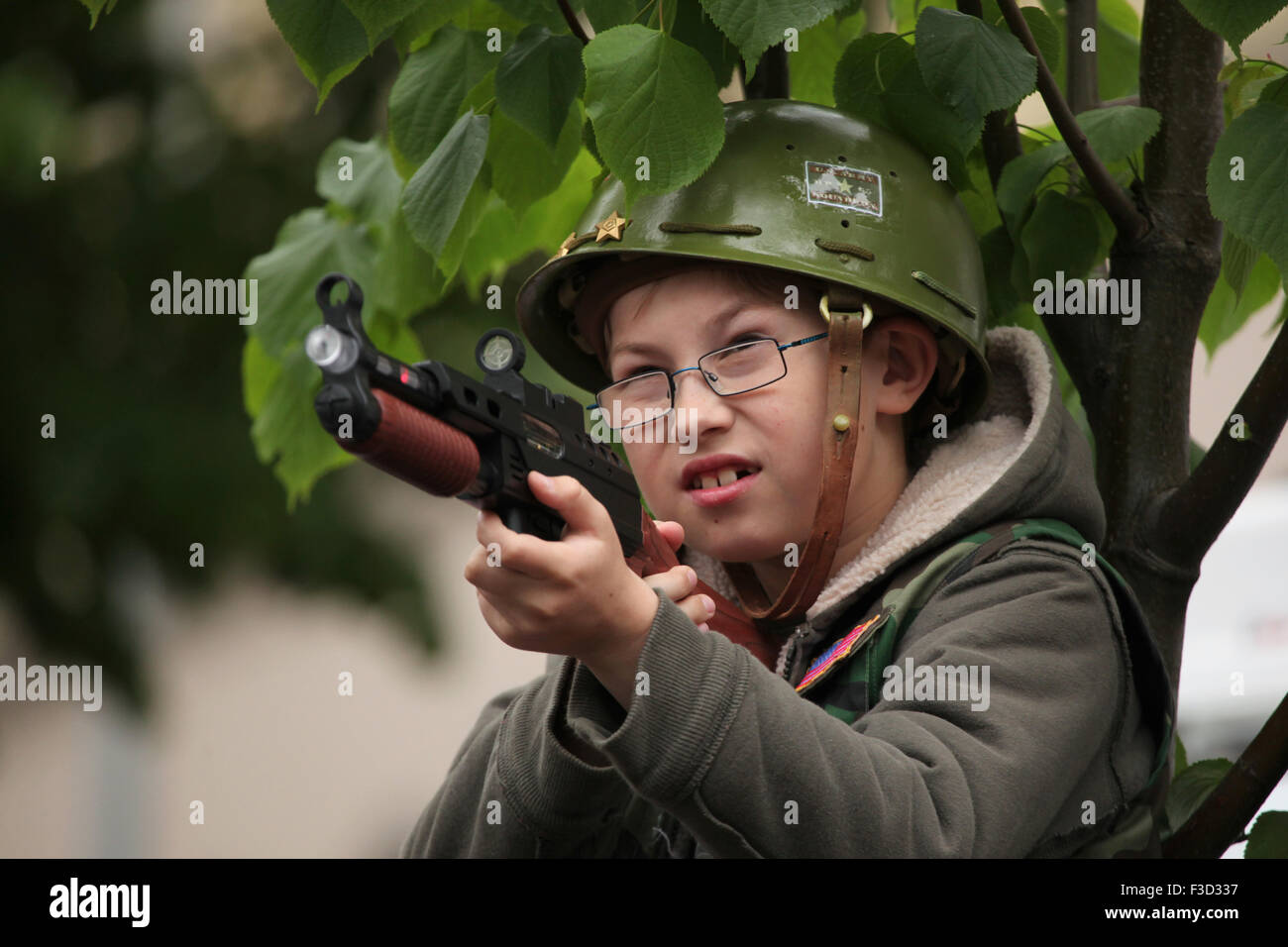 Ein kleiner Junge mit einem US-Armee Helm will mit der Spielzeugpistole während die Nachstellung der Prager 1945 Aufstand in Prag, Tschechische Republik, am 9. Mai 2015. Stockfoto