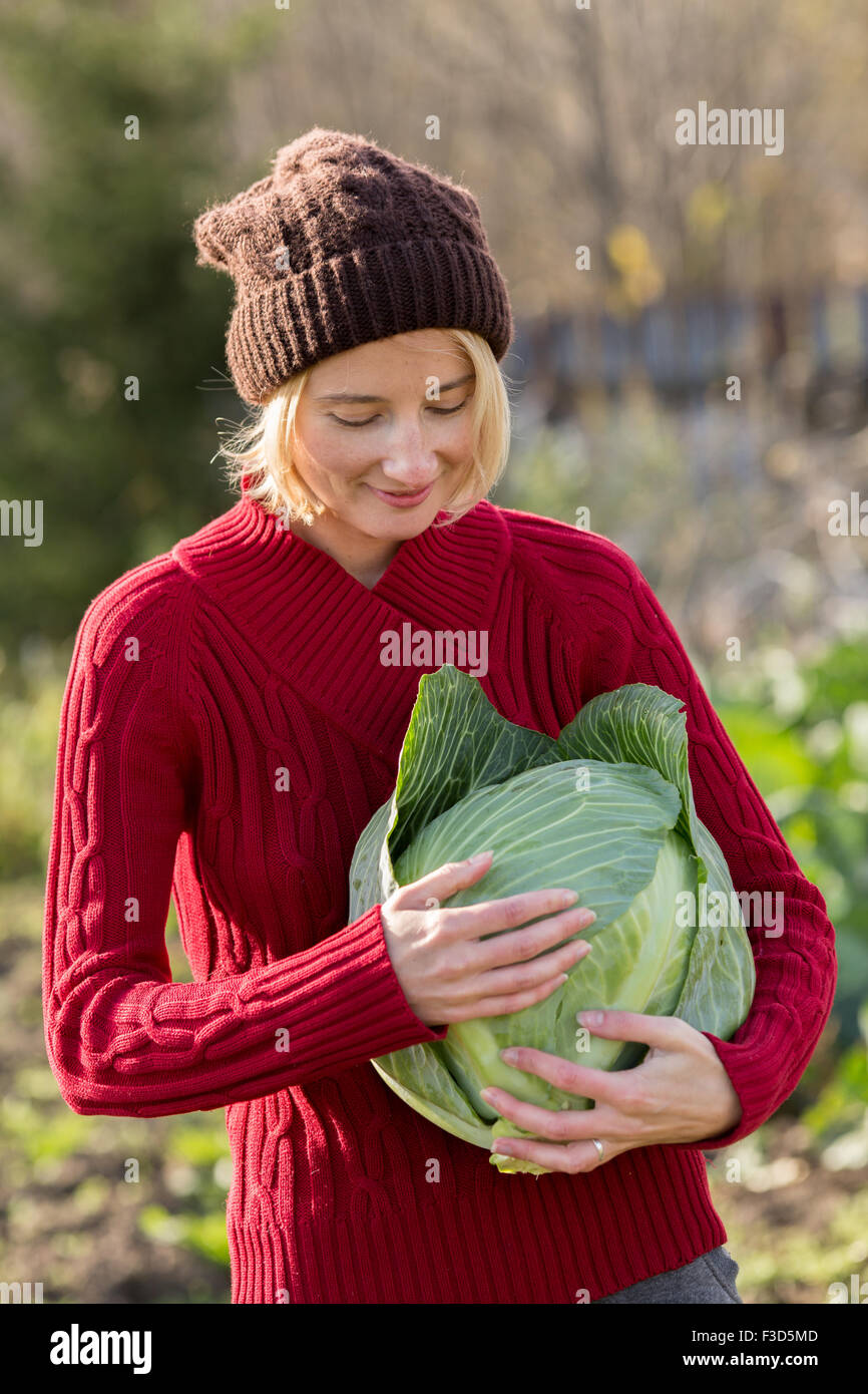 Lächelnde Frau hält und prüft einen frisch geerntete Kohl.  Ernte, lokale Landwirtschaft, Locavore Movenet Konzept. Selektiven Fokus auf Stockfoto