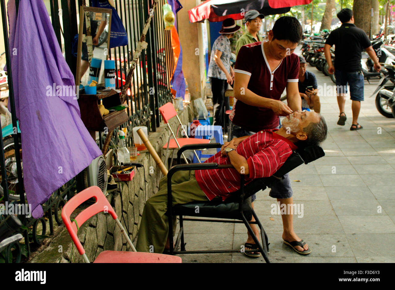 Ein Mann hat eine Rasur bei Streetside Barbier in Ho-Chi-Minh-Stadt, Vietnam Stockfoto