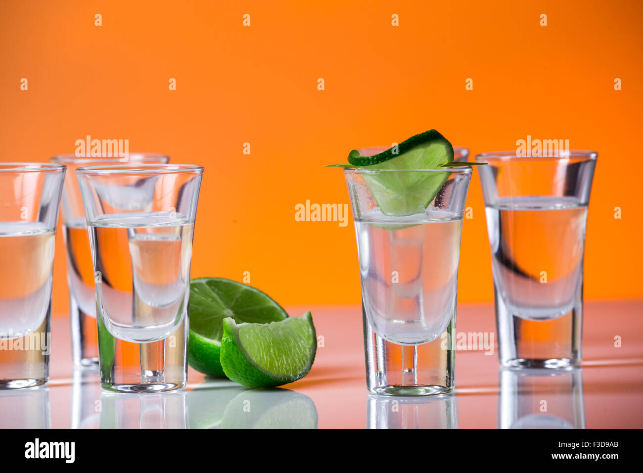 Tequila shot mit einer Scheibe Limette auf dem Glas auf orangem Hintergrund. Selektiven Fokus Stockfoto