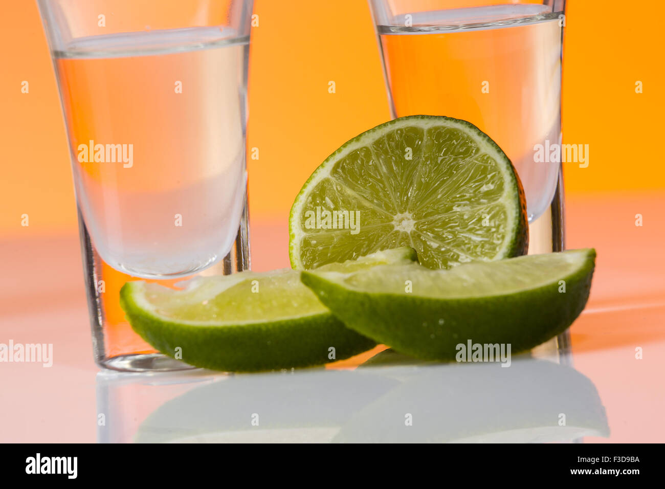 Tequila shot mit einer Scheibe Limette auf dem Glas auf orangem Hintergrund. Selektiven Fokus Stockfoto