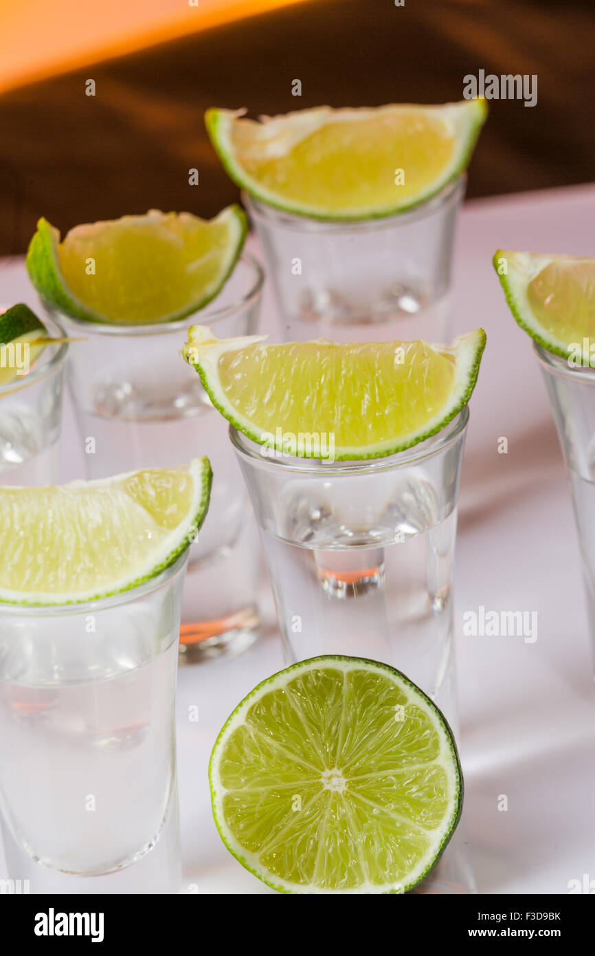 Tequila shot mit einer Scheibe Limette auf dem Glas auf orangem Hintergrund. Selektiven Fokus Stockfoto