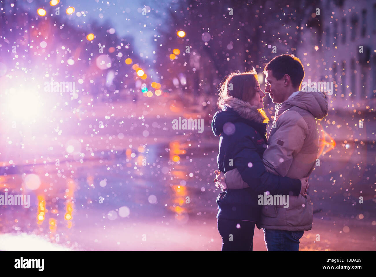 In Liebe Paar küssen im Schnee bei Nacht Stadtstraße. Gefiltert mit Korn und Licht blinkt Stockfoto