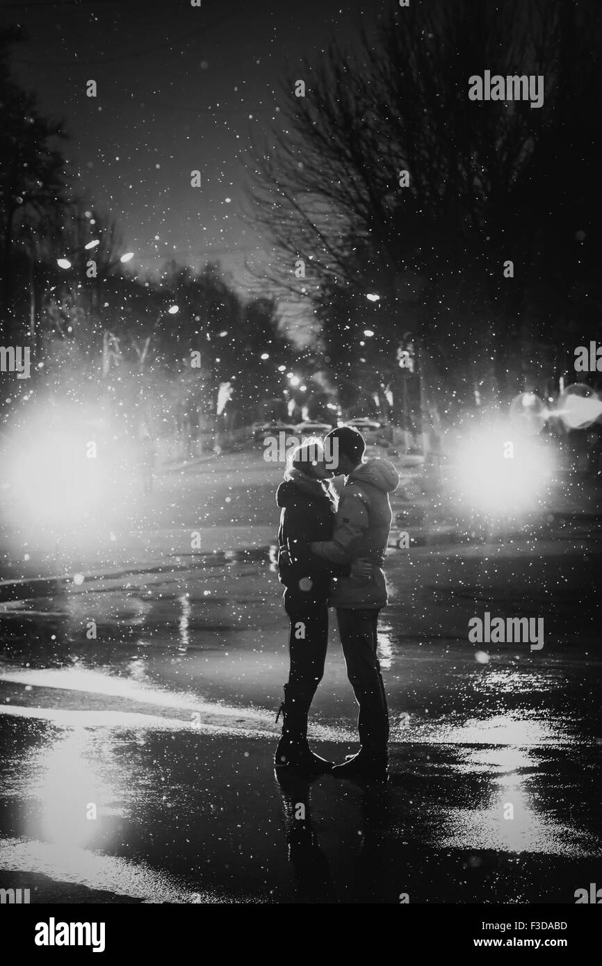 In Liebe Paar küssen im Schnee bei Nacht Stadt Straße schwarz / weiß Stockfoto