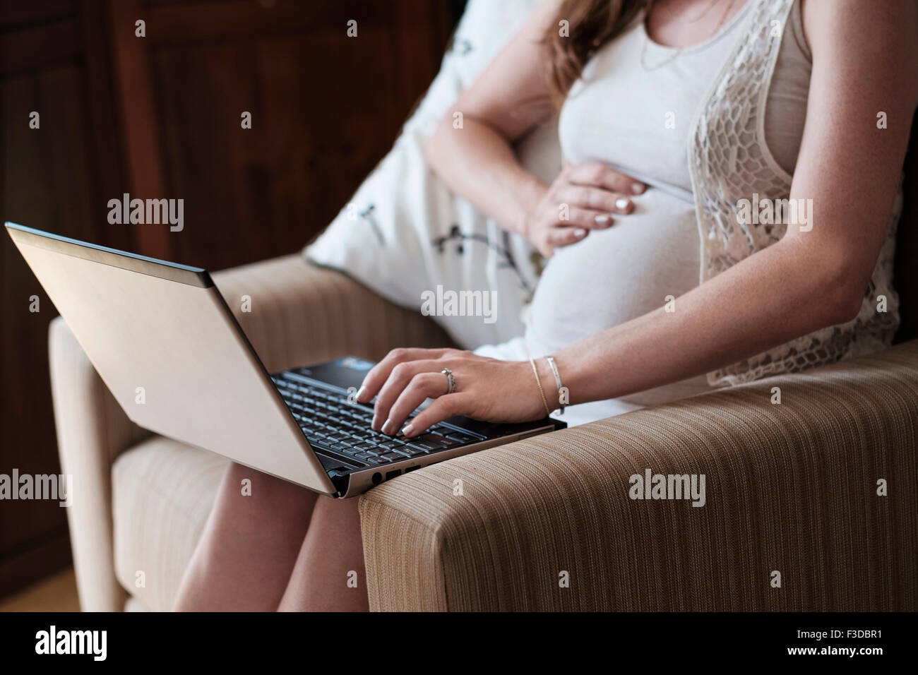 Mittelteil der schwangeren Frau mit laptop Stockfoto