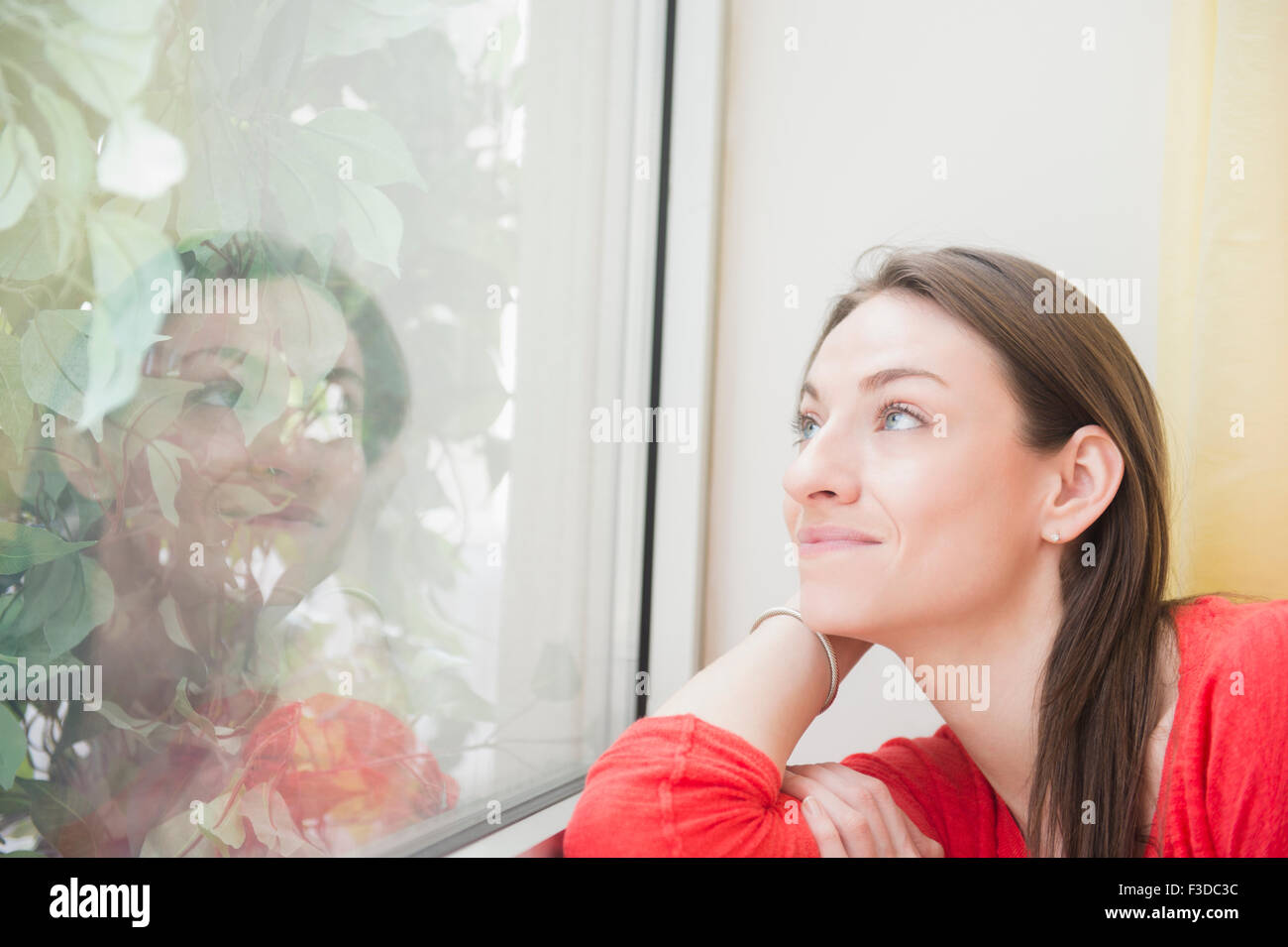 Lächelnde Frau Blick durch Fenster Stockfoto