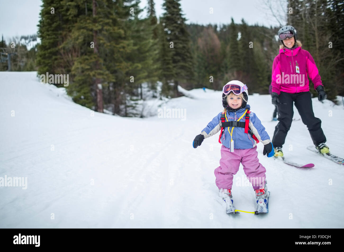 Kleines Mädchen (2-3) lernen Skifahren mit Mutter Stockfoto