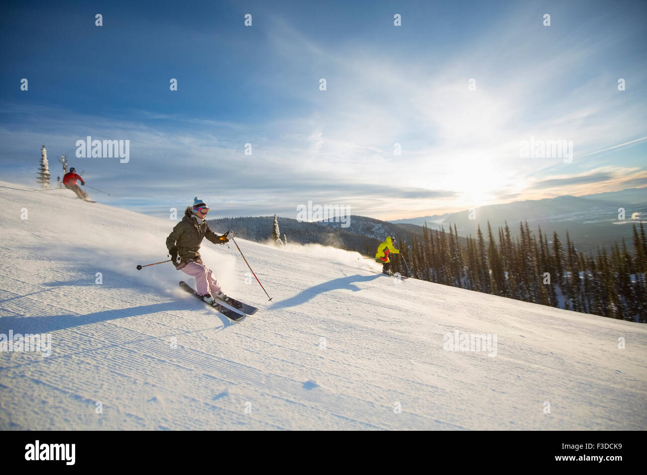 Drei Menschen auf der Skipiste im Sonnenlicht Stockfoto
