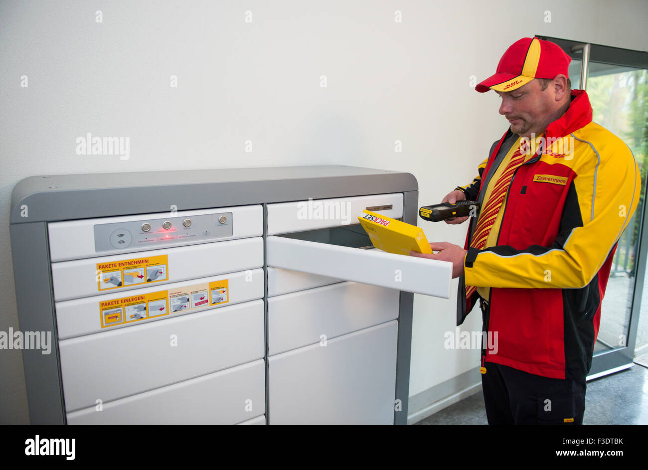 Berlin, Deutschland. 6. Oktober 2015. Bote Marko Zimmermann steht vor Paket Briefkästen für Mietshäuser in einem Apartment-Komplex in Berlin, Deutschland, 6. Oktober 2015. Während einer Pressekonferenz Einweisung den Konzern Deutsche Post DHL auf das Pilotprojekt mit der Baufirma Vonovia, die seit Mai 2015 laufenden ist. Das Projekt ermöglicht es Mietern zu versuchen, diese neue Option Versand und Lieferung. Foto: BERND VON JUTRCZENKA/Dpa/Alamy Live-Nachrichten Stockfoto