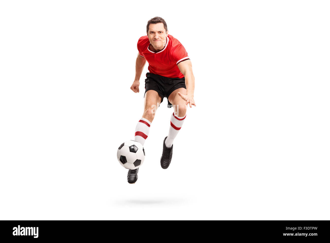 Junge Sportler treten einen Fußball in der Luft und schaut in die Kamera, die isoliert auf weißem Hintergrund Stockfoto