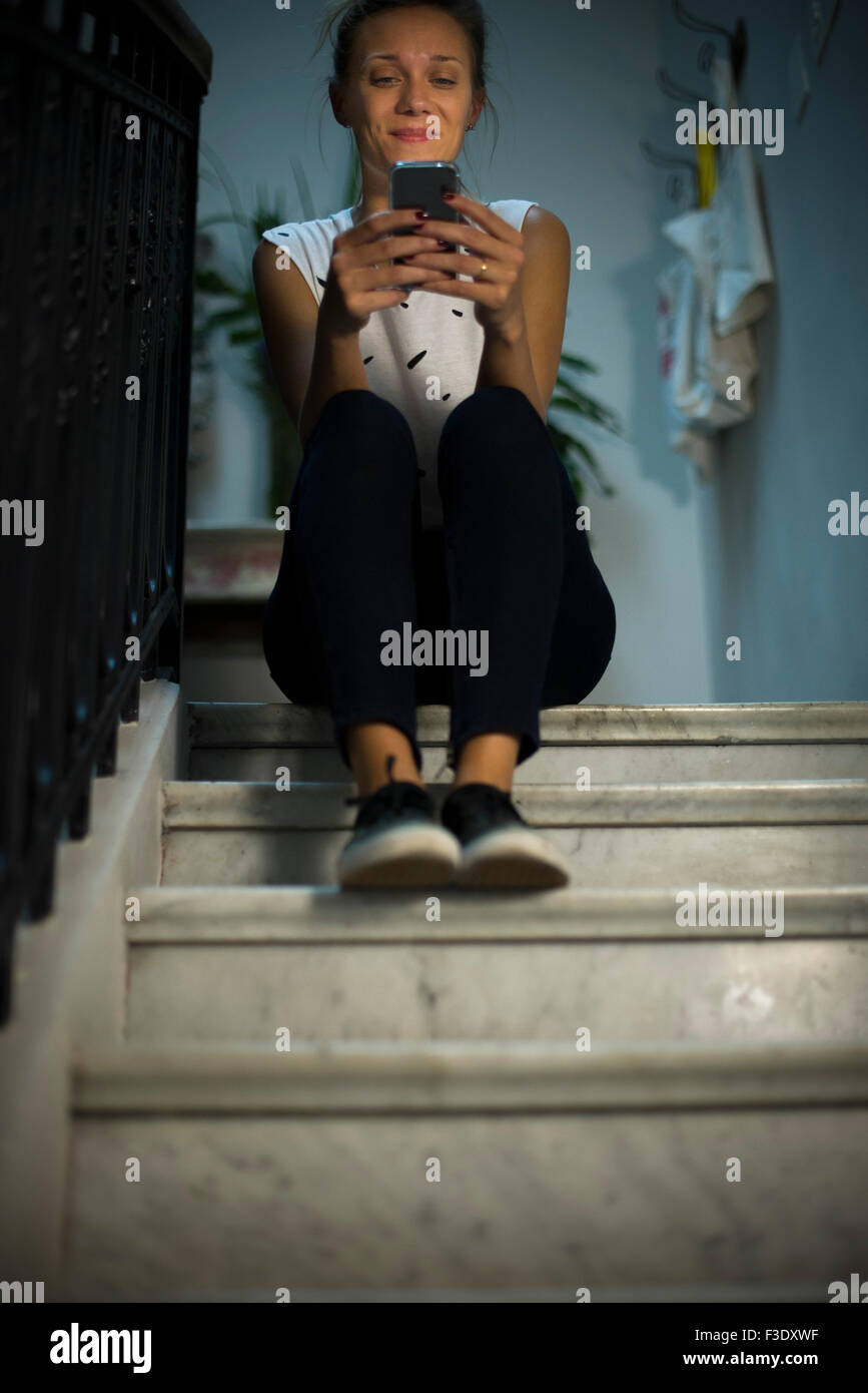 Frau sitzt auf der Treppe, mit smartphone Stockfoto