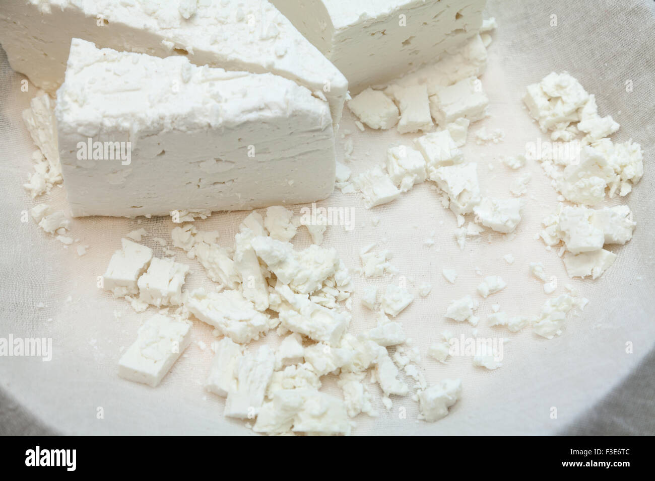Käseprodukte: Raw weichen mediterranes Feta weiß Käsewürfel und Runde am weißen Stoff in Platte. Stockfoto