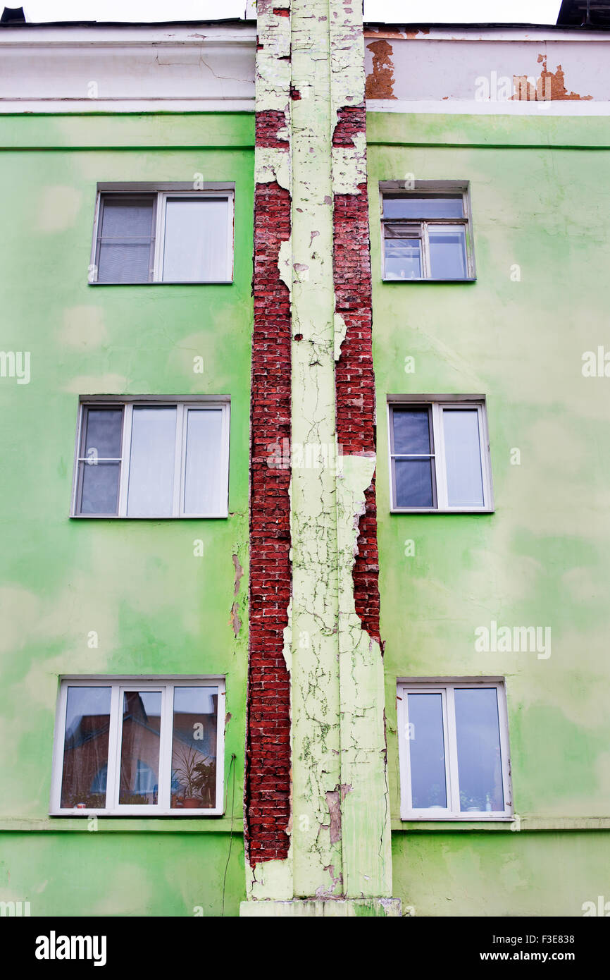 Grün geknackt Putz auf rote Backsteinhaus mit Windows. Ansicht von unten Stockfoto