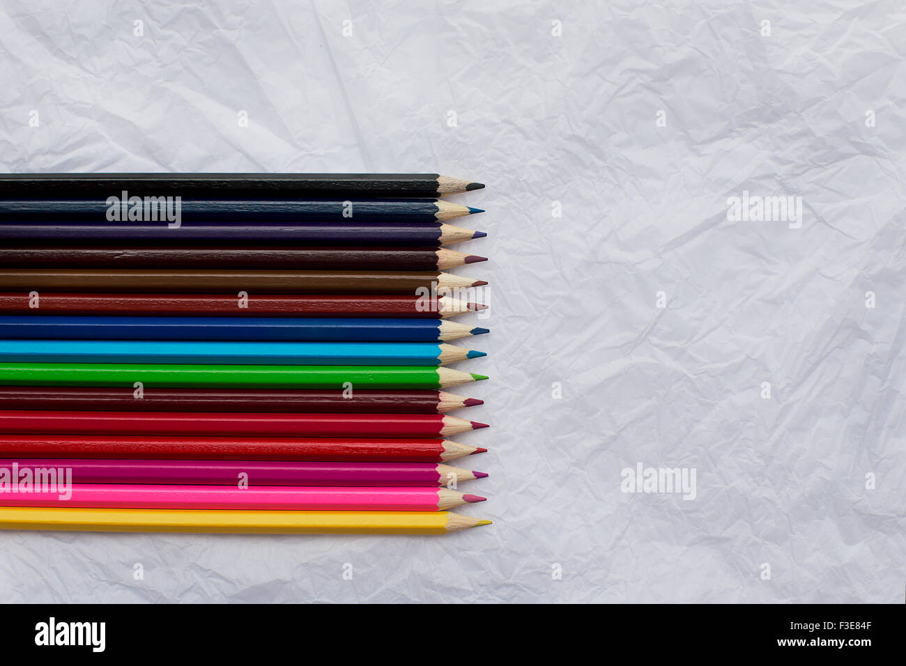 Buntstifte in einer Reihe auf zerknüllten weißen Blatt Papier Stockfoto