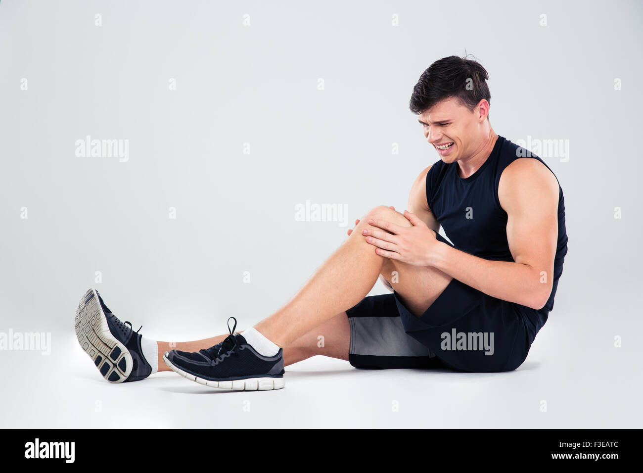 Porträt eines Fitness mit Schmerzen in einem Knie isoliert auf weißem Hintergrund Stockfoto