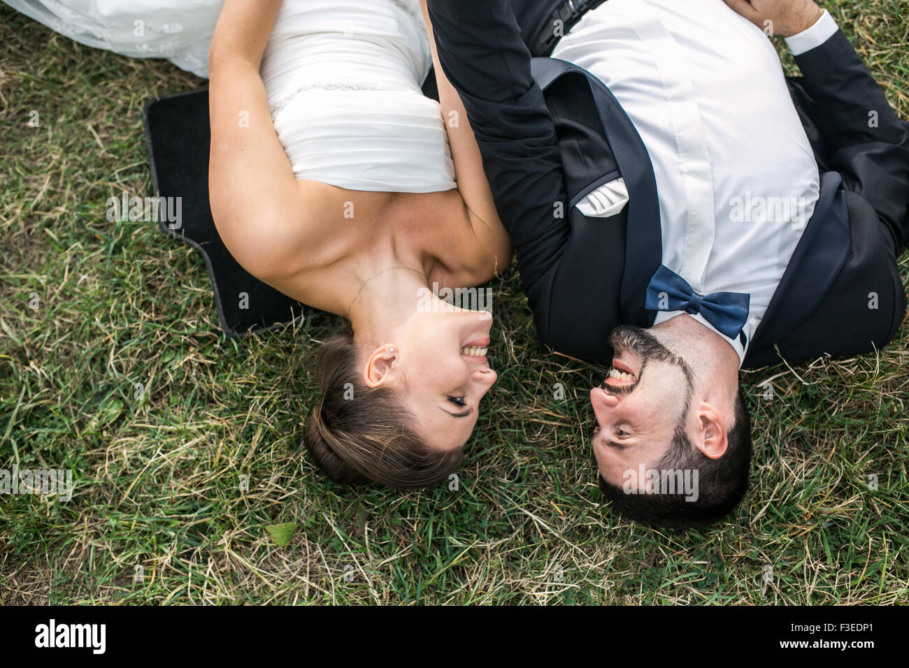 Hochzeitspaar liegen auf dem Rasen vor der Kamera Stockfoto