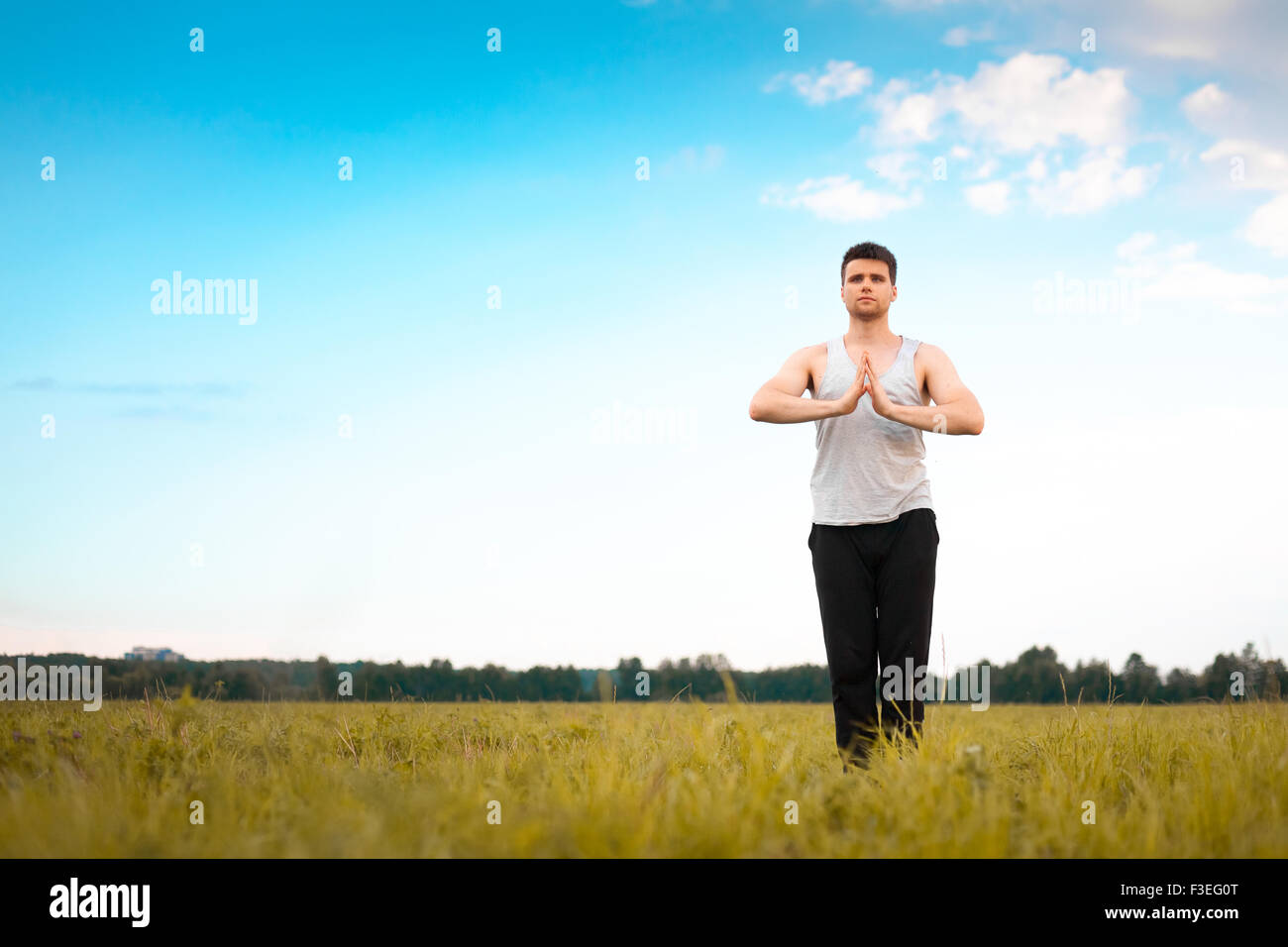 Junger Mann beim Yoga im park Stockfoto