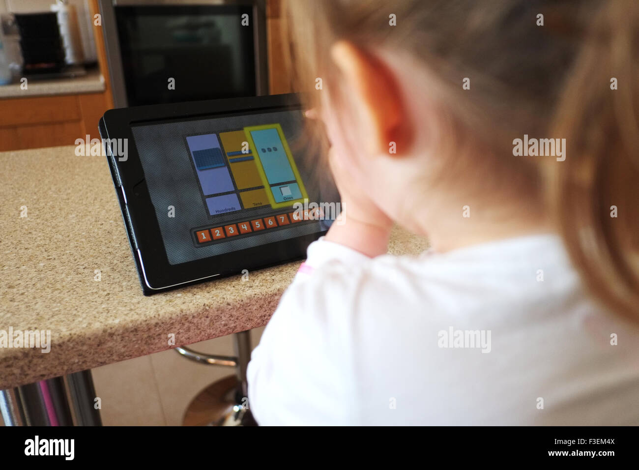 Ein kleines Kind zu Hause verwenden einen Ipad-Computer, melden Sie sich im Internet und lernen spielen ein Spiel Lernanwendung Stockfoto
