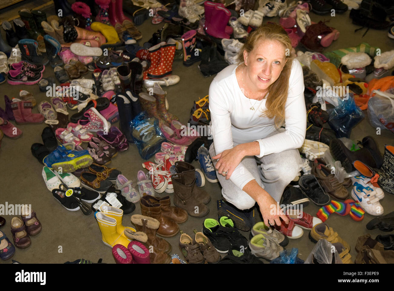 Mitbegründer von einem Spendenaufruf, Flüchtlinge, die Krieg zerrissenen umgeben von einigen der gespendeten Schuhe für Syrien zu helfen... Stockfoto