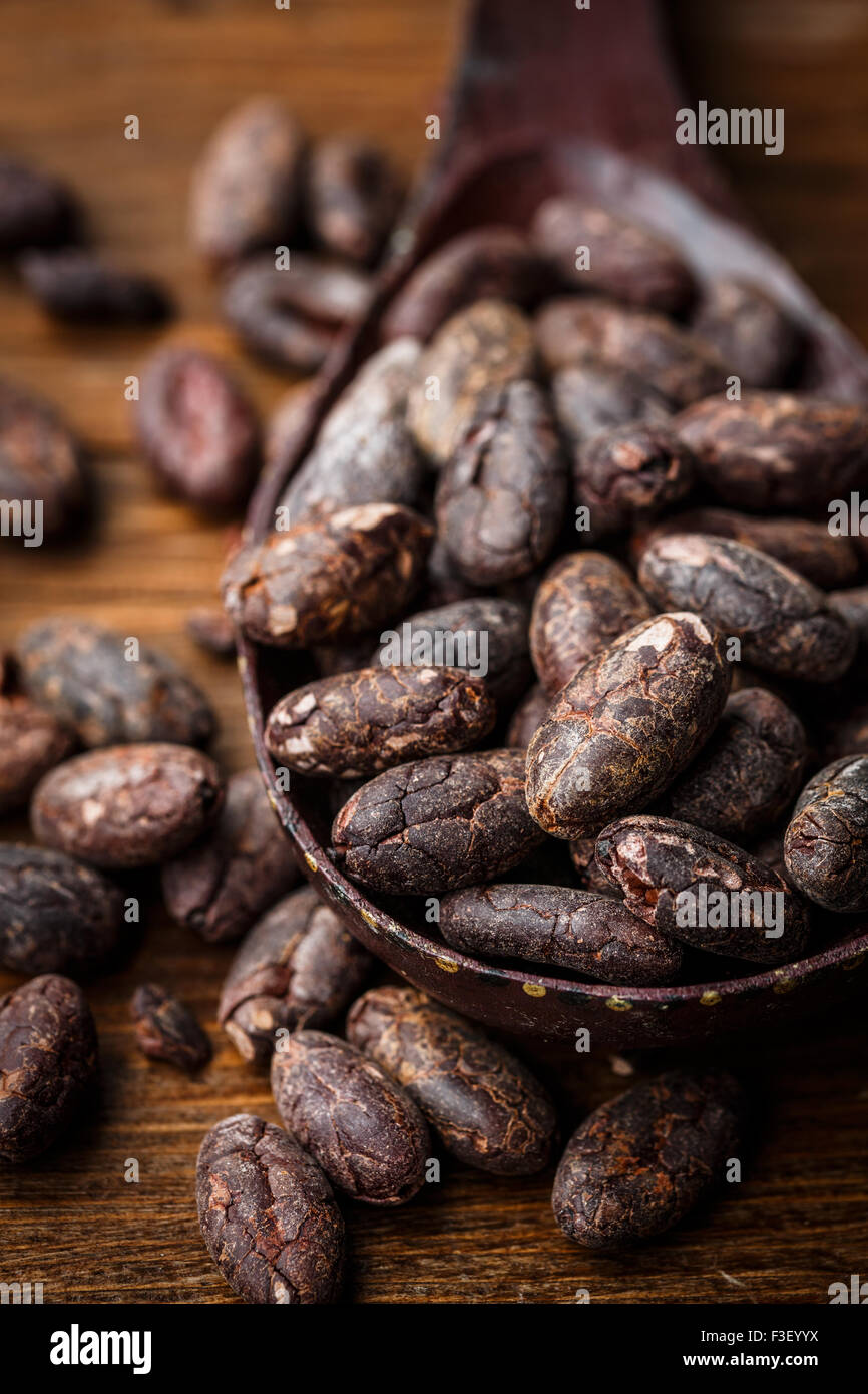 Rohe Kakaobohnen auf einem Löffel auf Holztisch Stockfoto