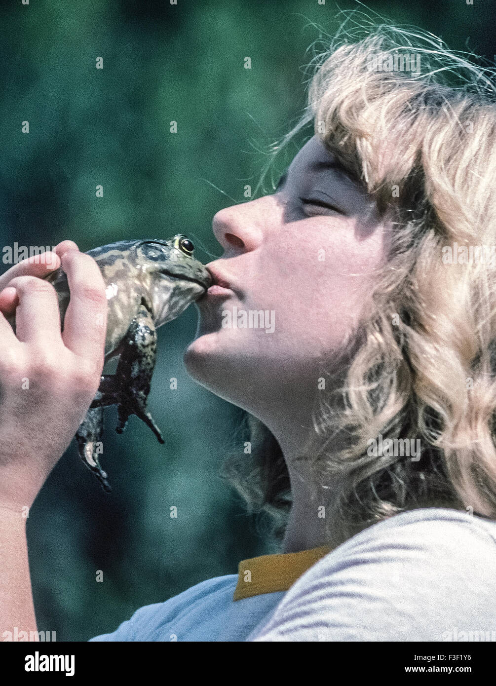 Ein junges Mädchen küsst ihr Frosch während ein Frosch springt Wettbewerb in Del Mar, Kalifornien, USA. Der gelegentliche Brauch, einen Frosch küssen bezieht sich auf ein Märchen über eine Prinzessin, die einen Frosch küsst und verwandelt die Amphibien in einen schönen Prinzen-- und sie leben glücklich bis ans Ende. Frosch Springturniere sind jährliche Veranstaltungen in einer Reihe von amerikanischen Gemeinschaften, einschließlich Calaveras County, Kalifornien, wo ein Frosch-Jubiläum seit 1928 stattgefunden hat. Der Wettbewerb entstand, nachdem amerikanische Schriftsteller Mark Twain (geb. Samuel Clemens) schrieb eine Kurzgeschichte "The feierte Jumping Frog von Calaveras County." Stockfoto