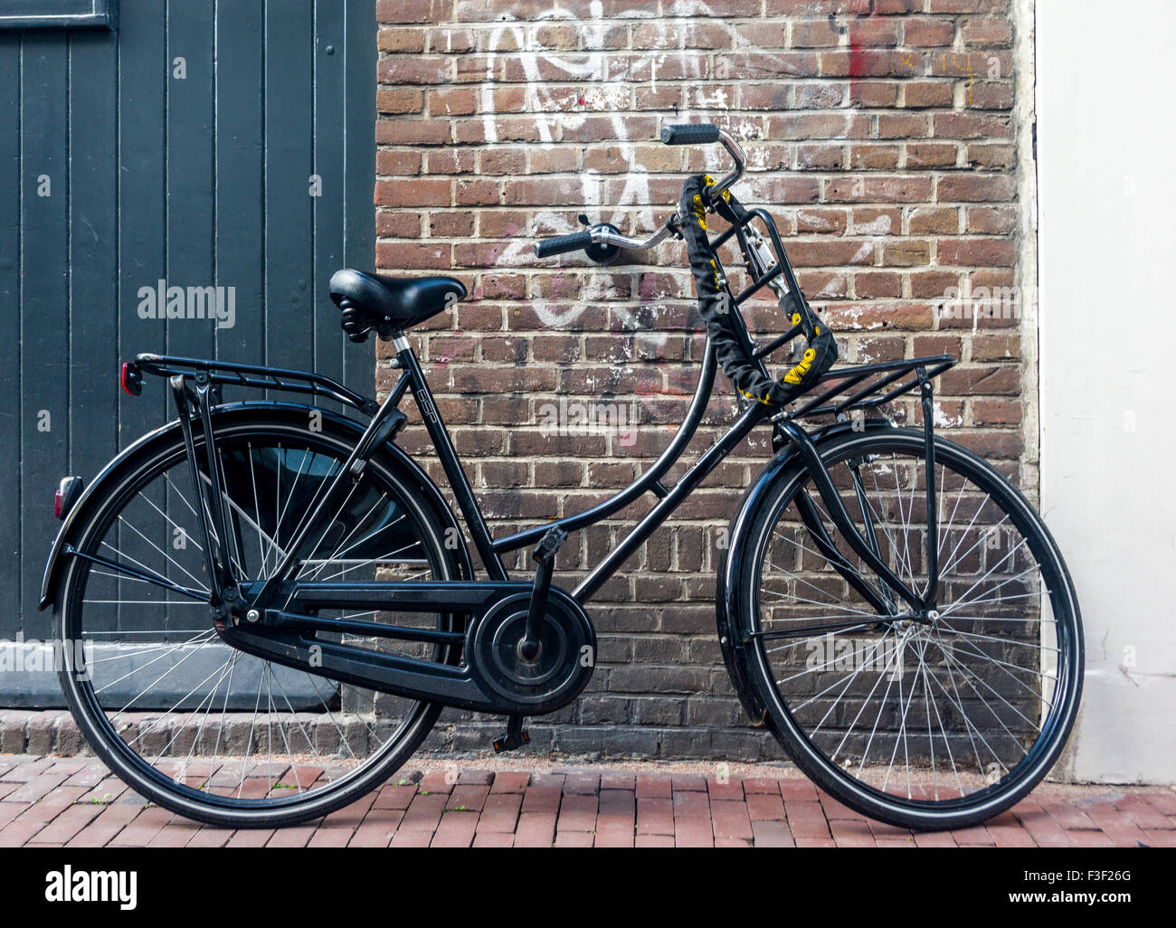 Ein Fahrrad parkt gegen eine Grafitti bewachsenen Mauer in Amsterdam, Niederlande. Stockfoto