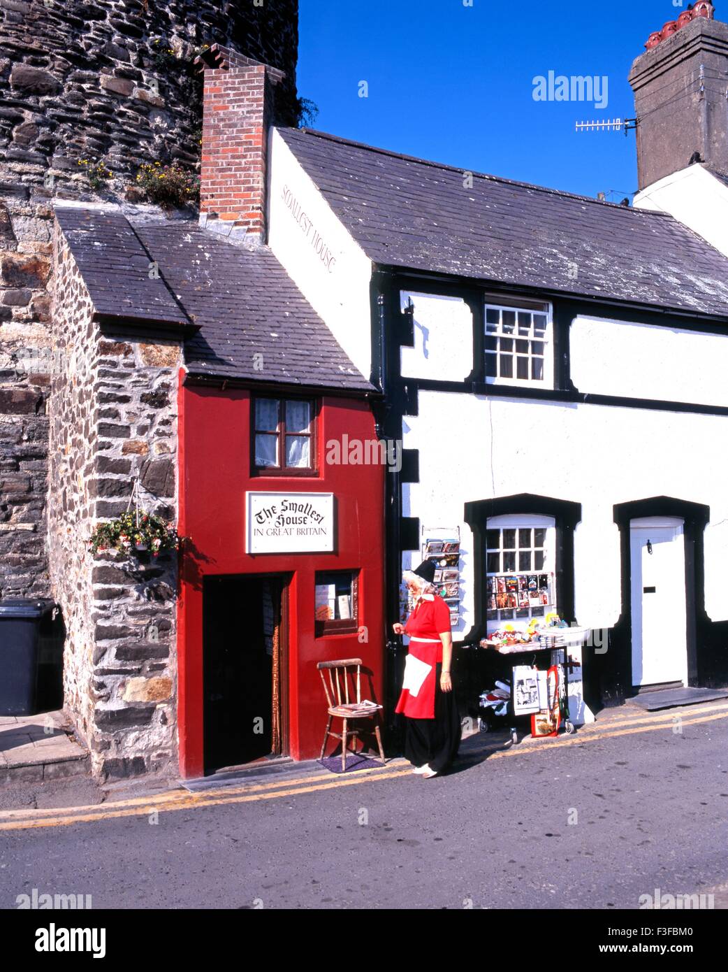 Das kleinste Haus in Großbritannien mit einer walisischen Dame in Tracht im Vordergrund, Conwy (Conway), Gwynedd, Wales. Stockfoto