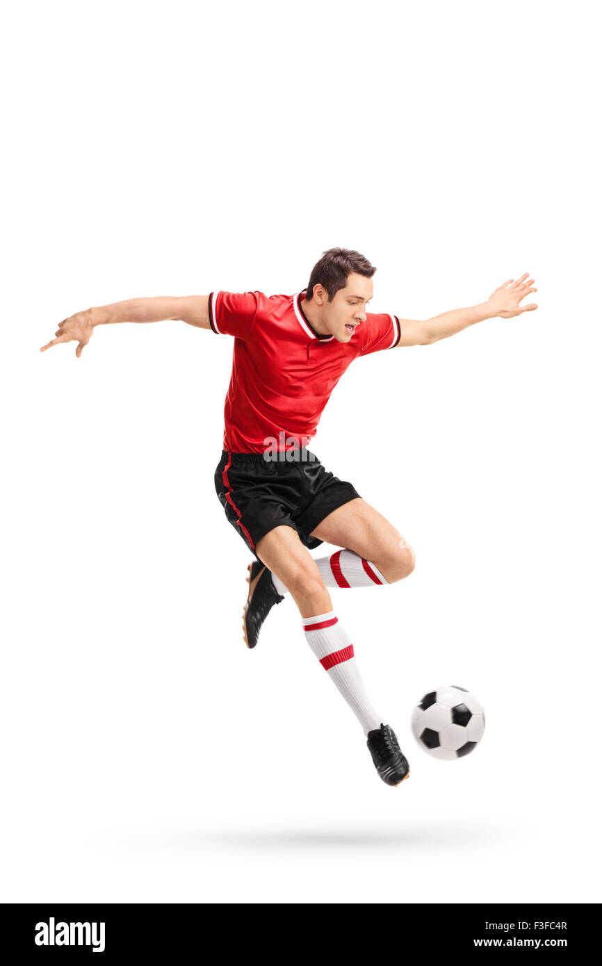 Voller Länge Porträt eines jungen Fußballspielers im roten Trikot, einen Ball in der Luft isoliert auf weißem Hintergrund Stockfoto