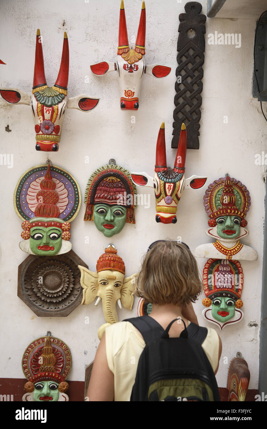 Touristen auf der Suche verschiedene Arten von Masken auf Wand lang angezeigt auf Mattancherry und Jude Street in Fort Kochi Kerala zu verkaufen Stockfoto