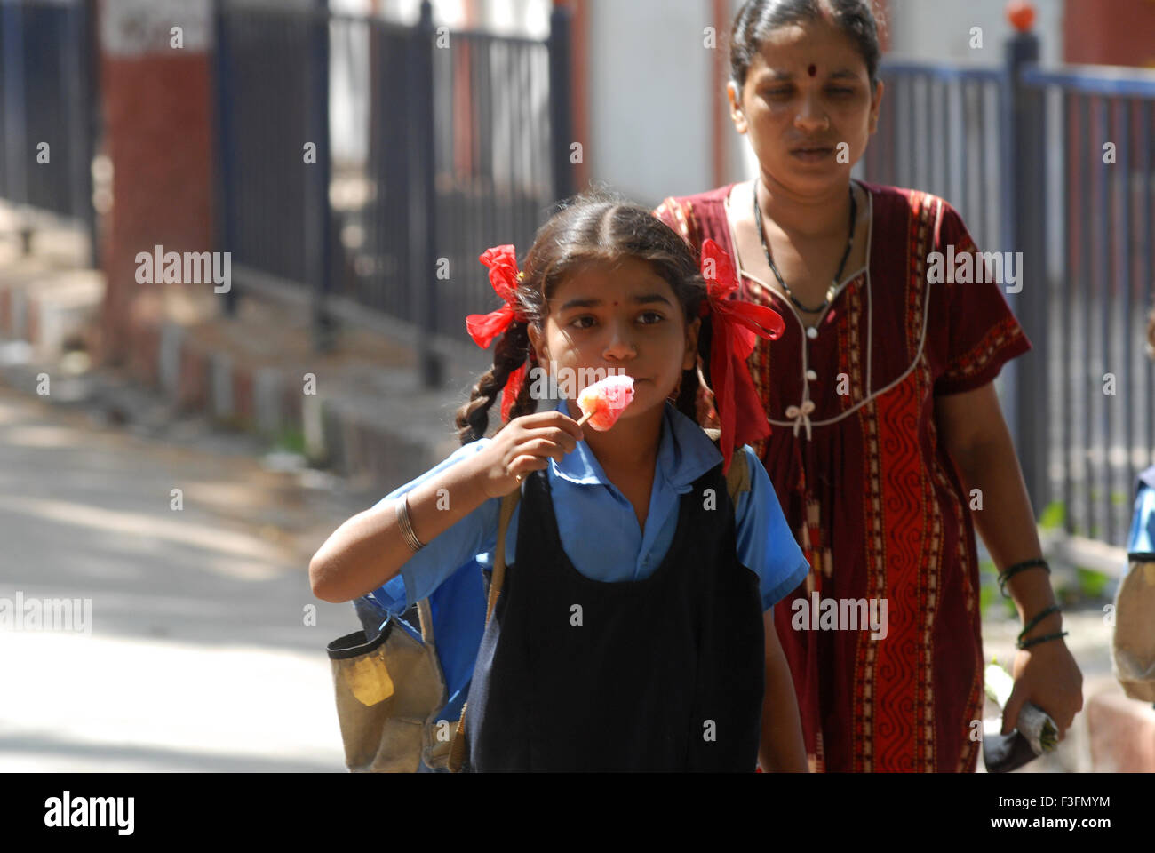 Ein Schulmädchen essen aromatisierte Eis Süßigkeiten; Bombay jetzt Mumbai; Maharashtra; Indien Stockfoto