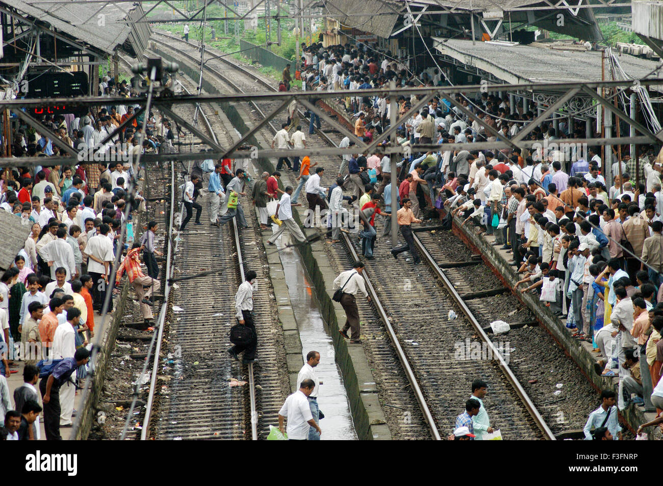 Pendler gefährlich Kreuz Gleisanlagen zu lokalen fangen trainieren unter Lebensgefahr bei Ghatkopar Railway Station Mumbai Stockfoto