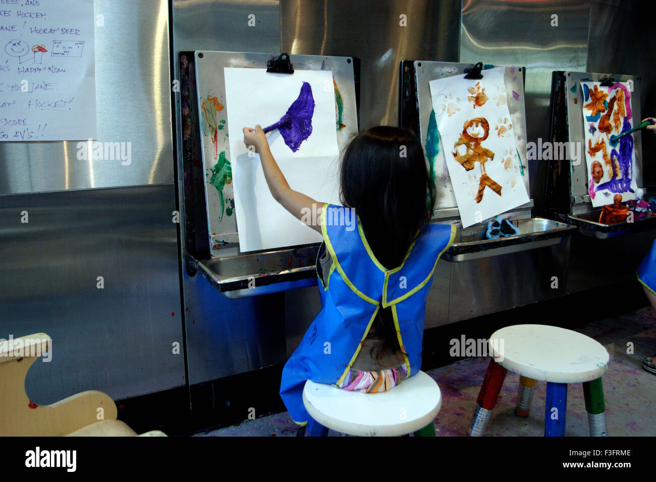 Mädchen mit Schürze und nahm Pinsel zu malen, die weiterhin für die Log-Zeit-Malerei auf Papier im Museum Stockfoto