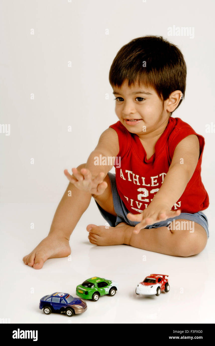 Indischer Junge spielt mit verschiedenen Modellen von Autos; HERR Stockfoto