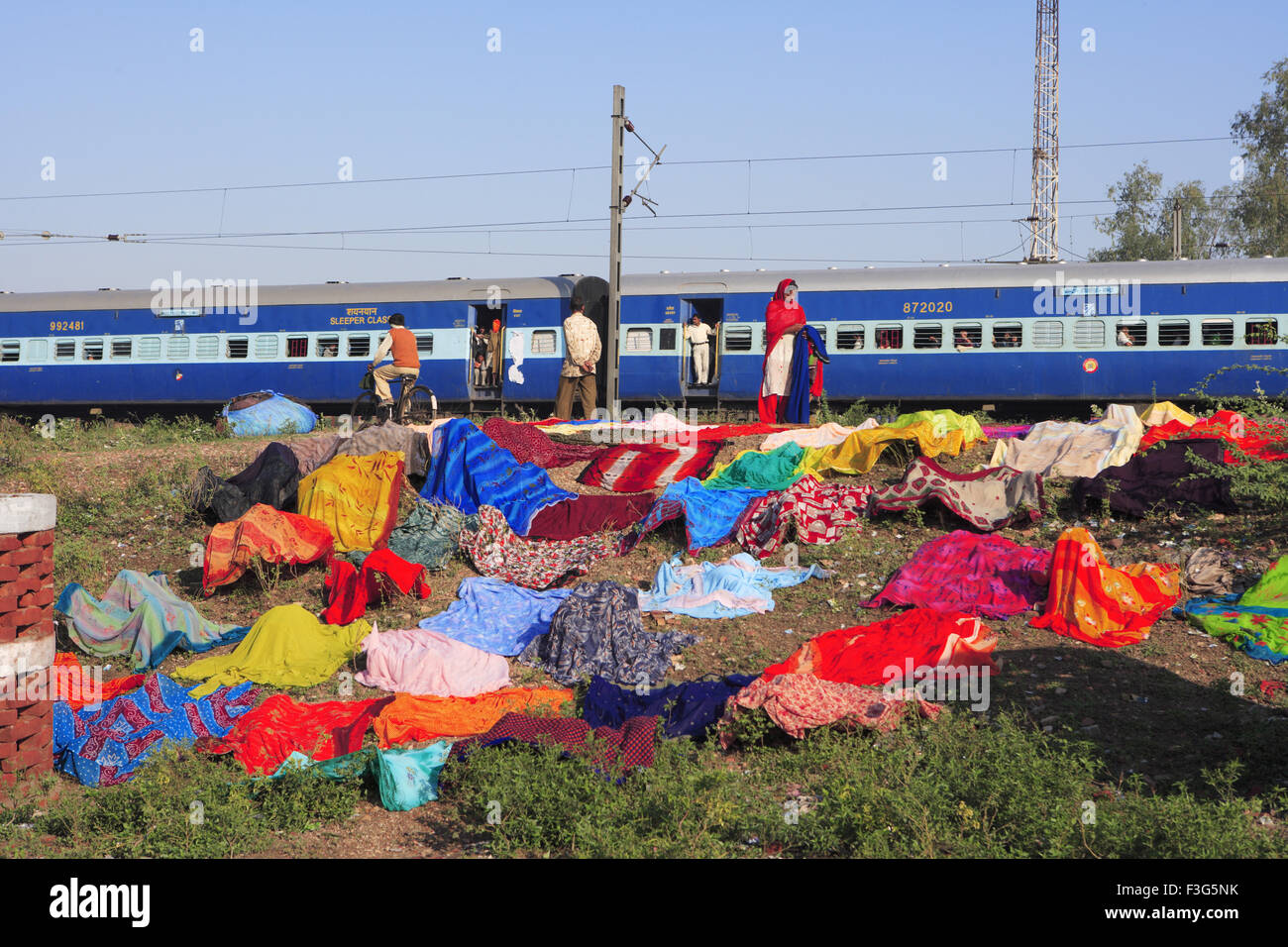 Frau Trocknen von Kleidung im Freien im Hintergrund der indischen Eisenbahn; Agra; Uttar Pradesh; Indien Stockfoto
