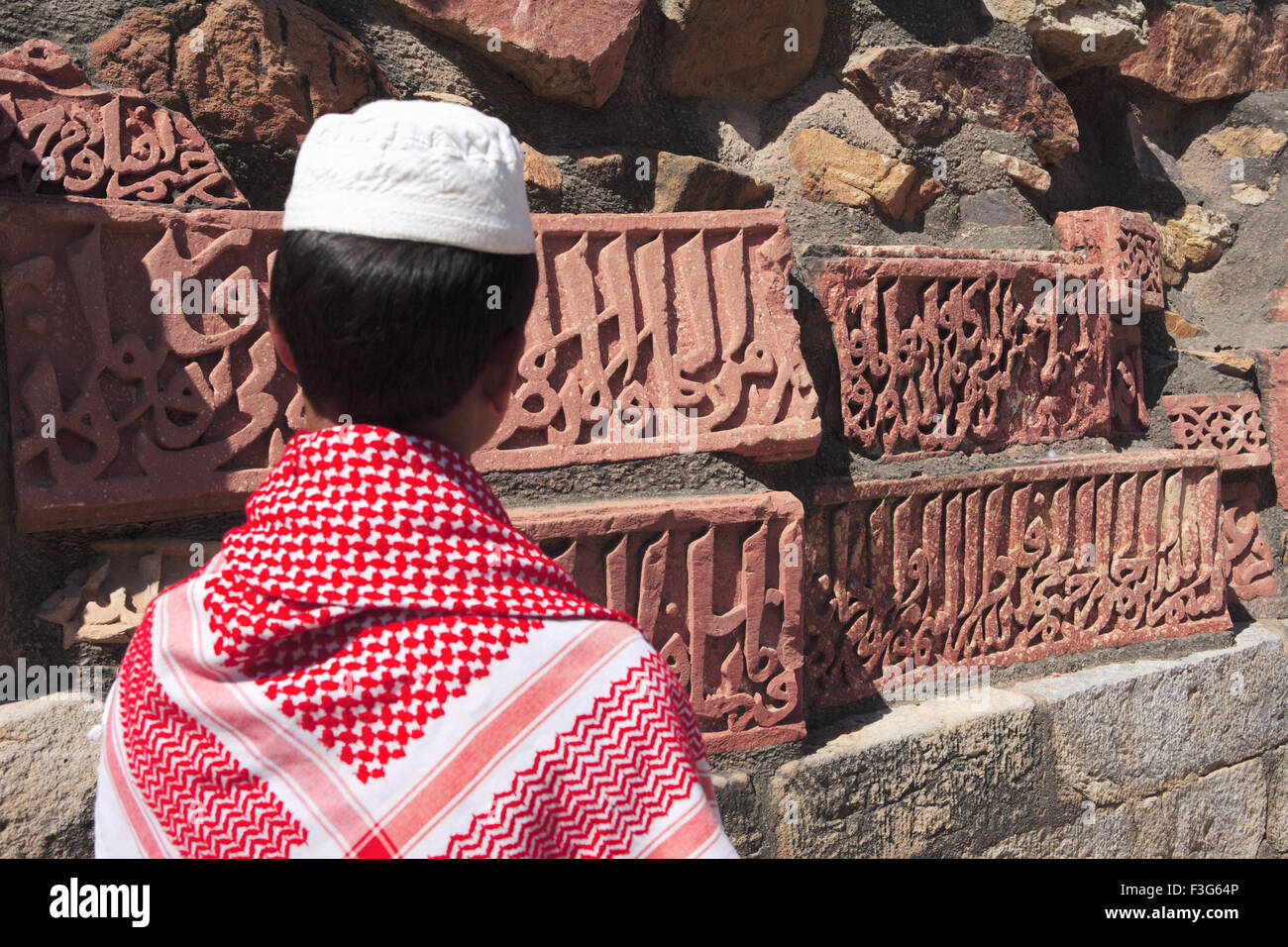 Muslimische Jungen beobachten Islamische Ornamentik des Quran Inschrift geschnitzt Qutab Minar Komplex aus rotem Sandstein Indo maurischer Kunst Delhi Stockfoto