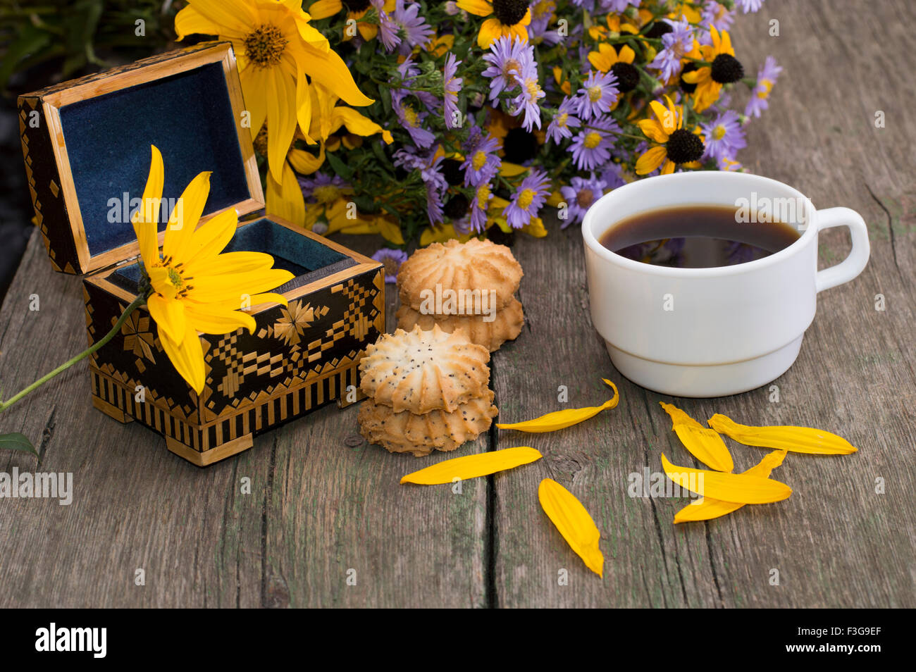 Schatulle, Kaffee, Kekse, Blütenblätter und Wildblumen auf ein alter Tisch, ein Stillleben, eine festliche Karte, Grußkarte, ein Thema zu öffnen Stockfoto