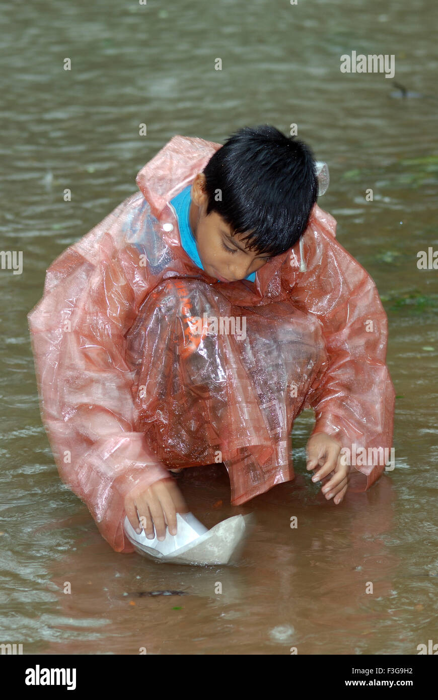Kind spielt mit Papierboot im Regen, Indien, Asien Stockfoto