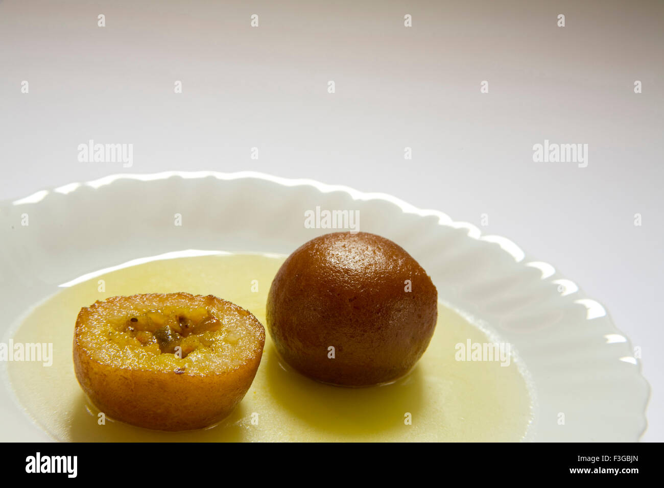 Indische Süßigkeiten eineinhalb Stück Runde Form Gulabjamun Bonbon Konditorei mit Zuckersirup im Teller serviert Stockfoto